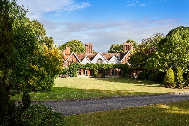 The exterior of a grand manor house surrounded by trees and grass