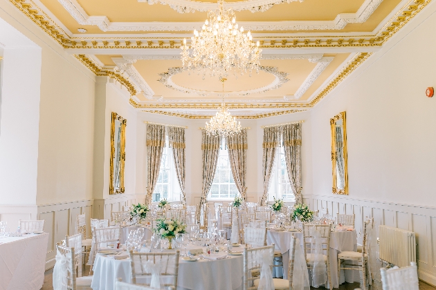 A bright space set up for a wedding breakfast with round tables and chairs